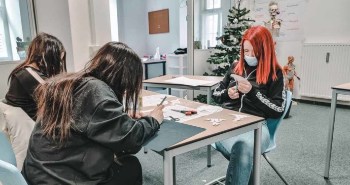 Schüler sitzen am Tisch und fertigen Scherenschnitte