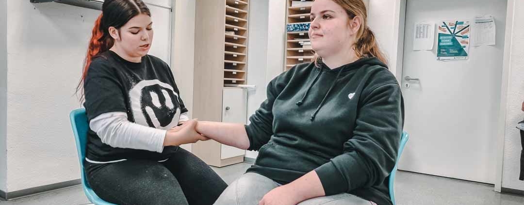 Auszubildende Pflegefachfrauen führen eine Handmassage durch