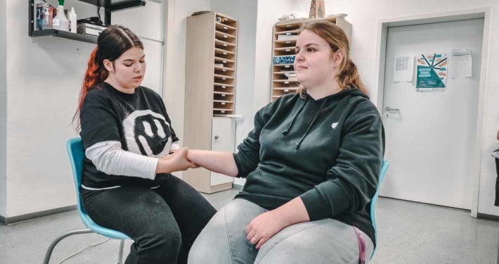 Auszubildende Pflegefachfrauen führen eine Handmassage durch